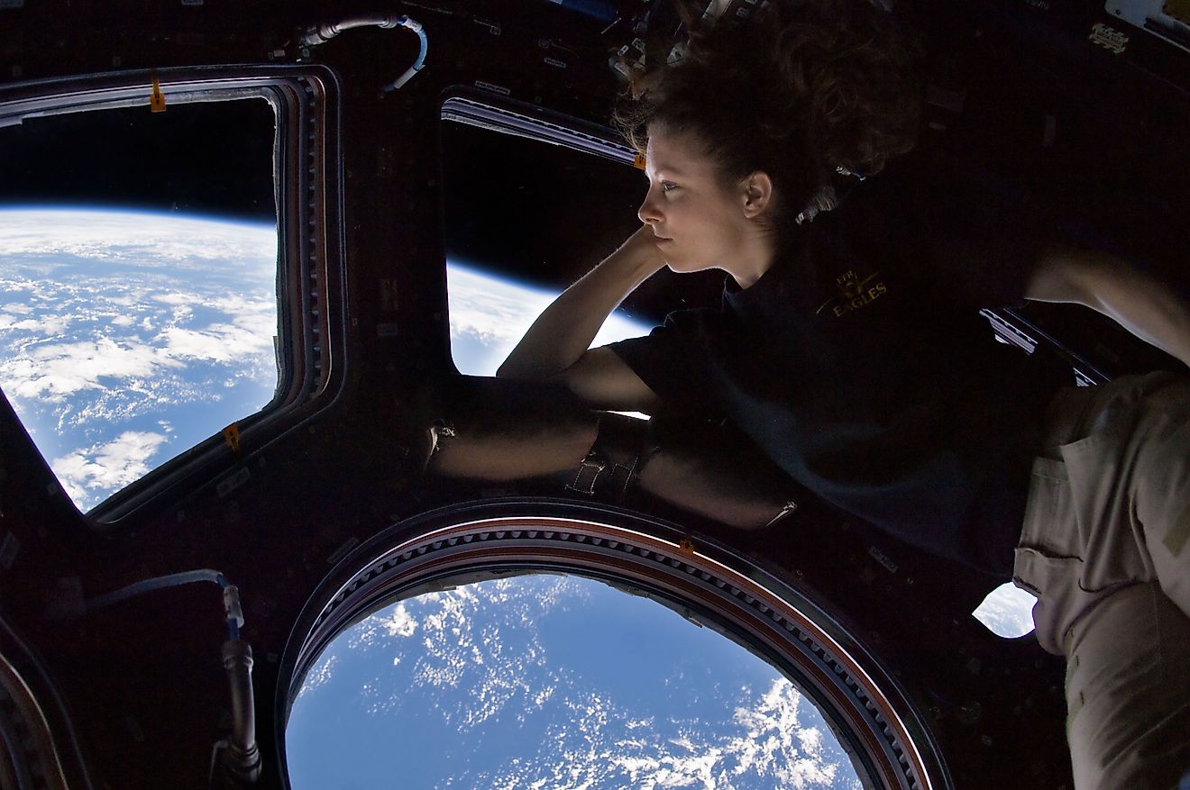 Self portrait of Tracy Caldwell Dyson in the International Space Station observing the Earth, who is taller in space compared to Earth. 