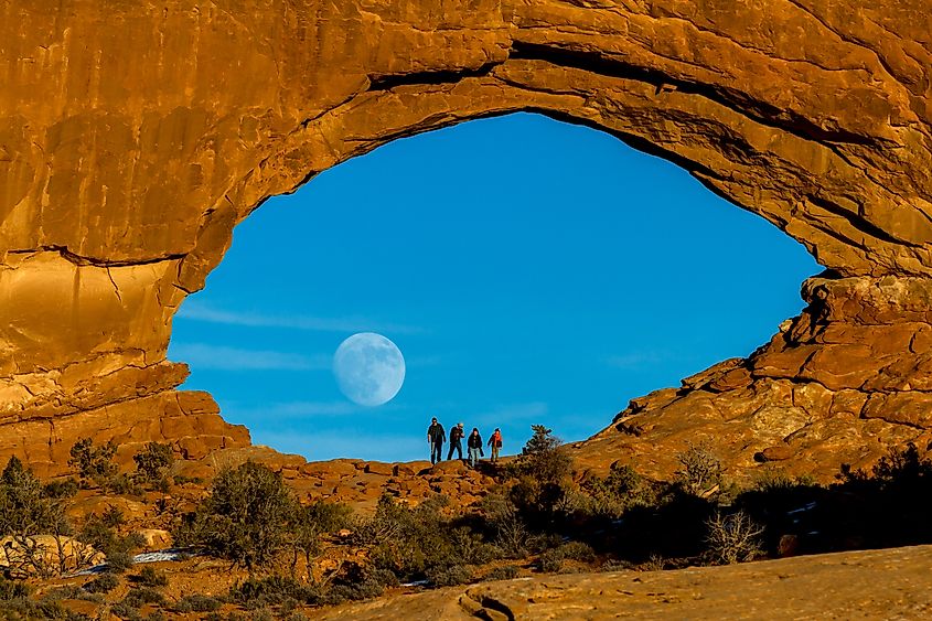 A full moon rising through North Window in Arches National Park, Utah
