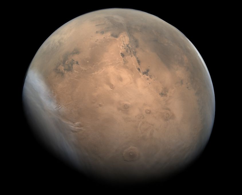 The reddish, cratered surface of Mars seen from orbit.
