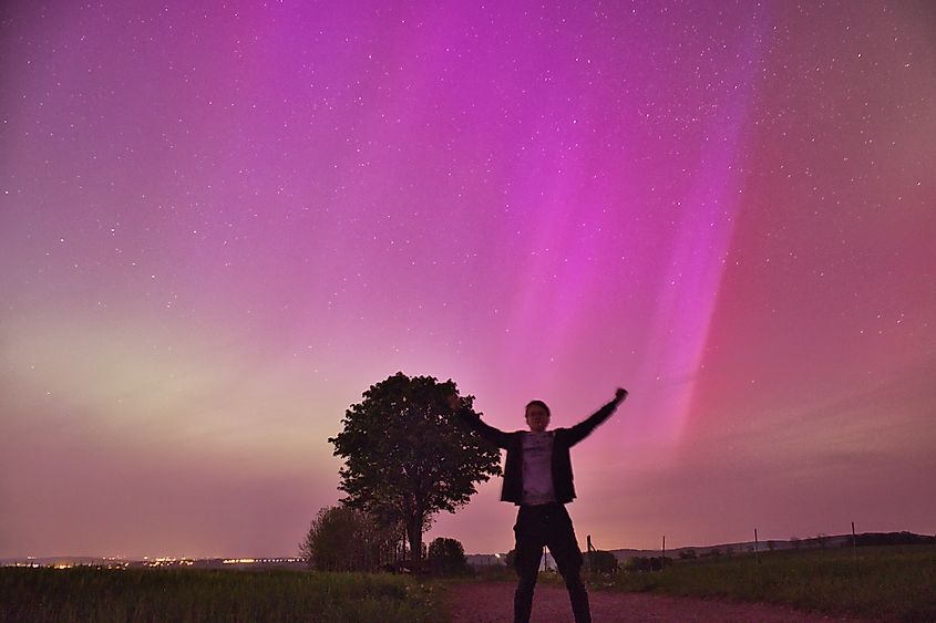 Amazed person waving hands under magical northern lights