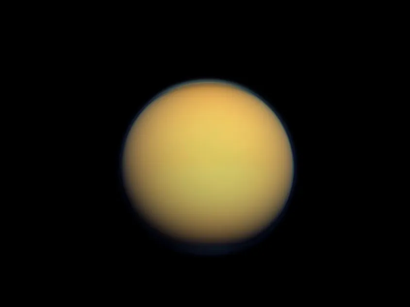 Titan seen as a hazy orange disc, its thick atmosphere hiding the surface.