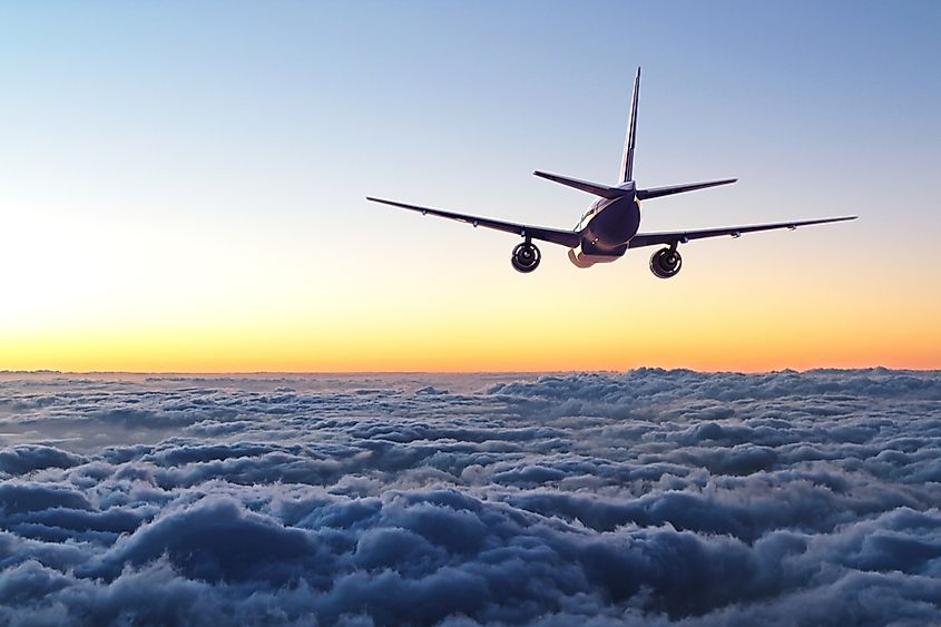 A commercial airliner in flight at high altitude above the clouds.